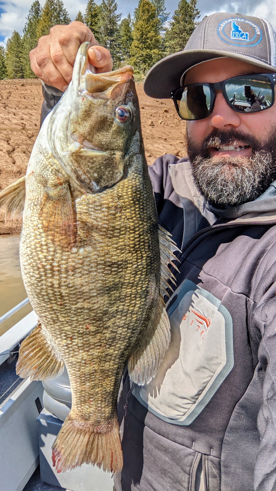 man poses with smallmouth bass