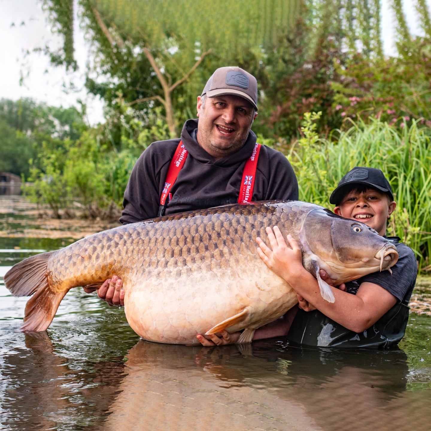 boy and father hold large carp