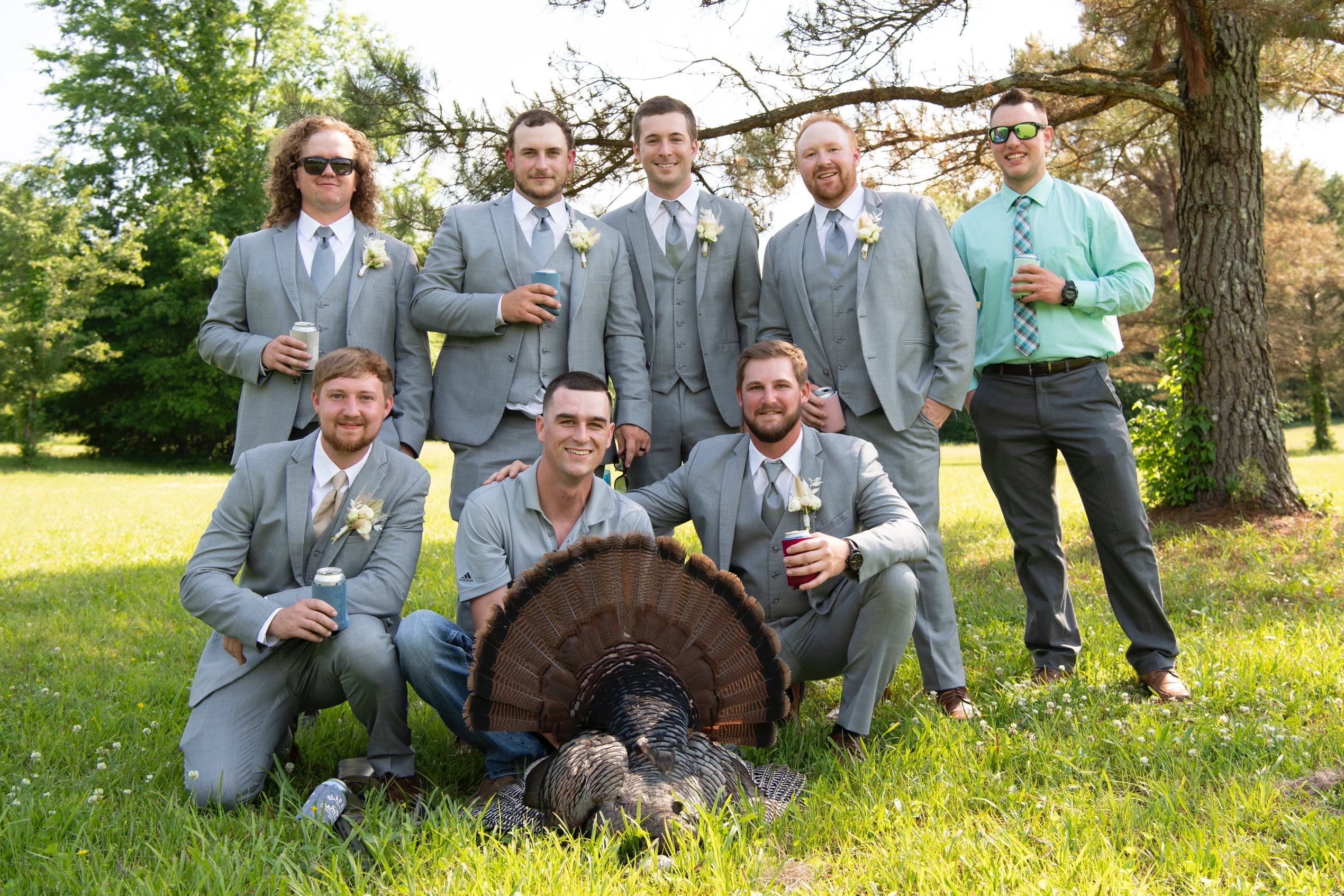 Groomsmen in suits pose with turkey