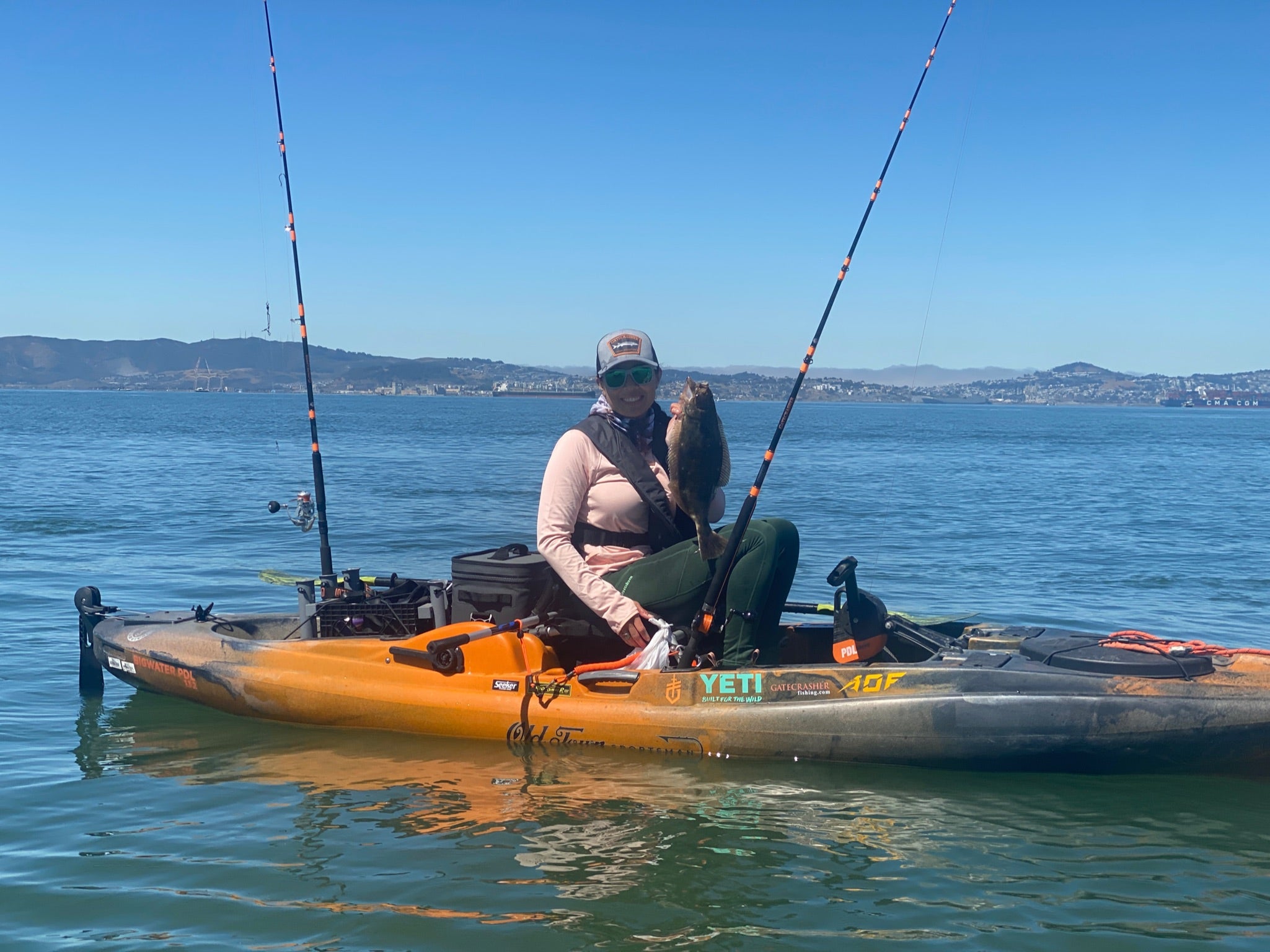 the fisherman holds the halibut from the kayak