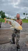 man holds white bighead carp for picture