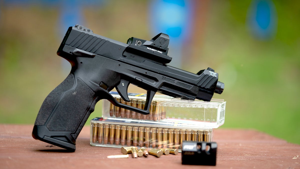 Handgun on a table balanced on two boxes of rimfire ammo.