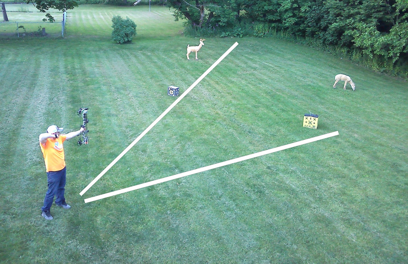 A man shooting a bow at four targets in his backyard.