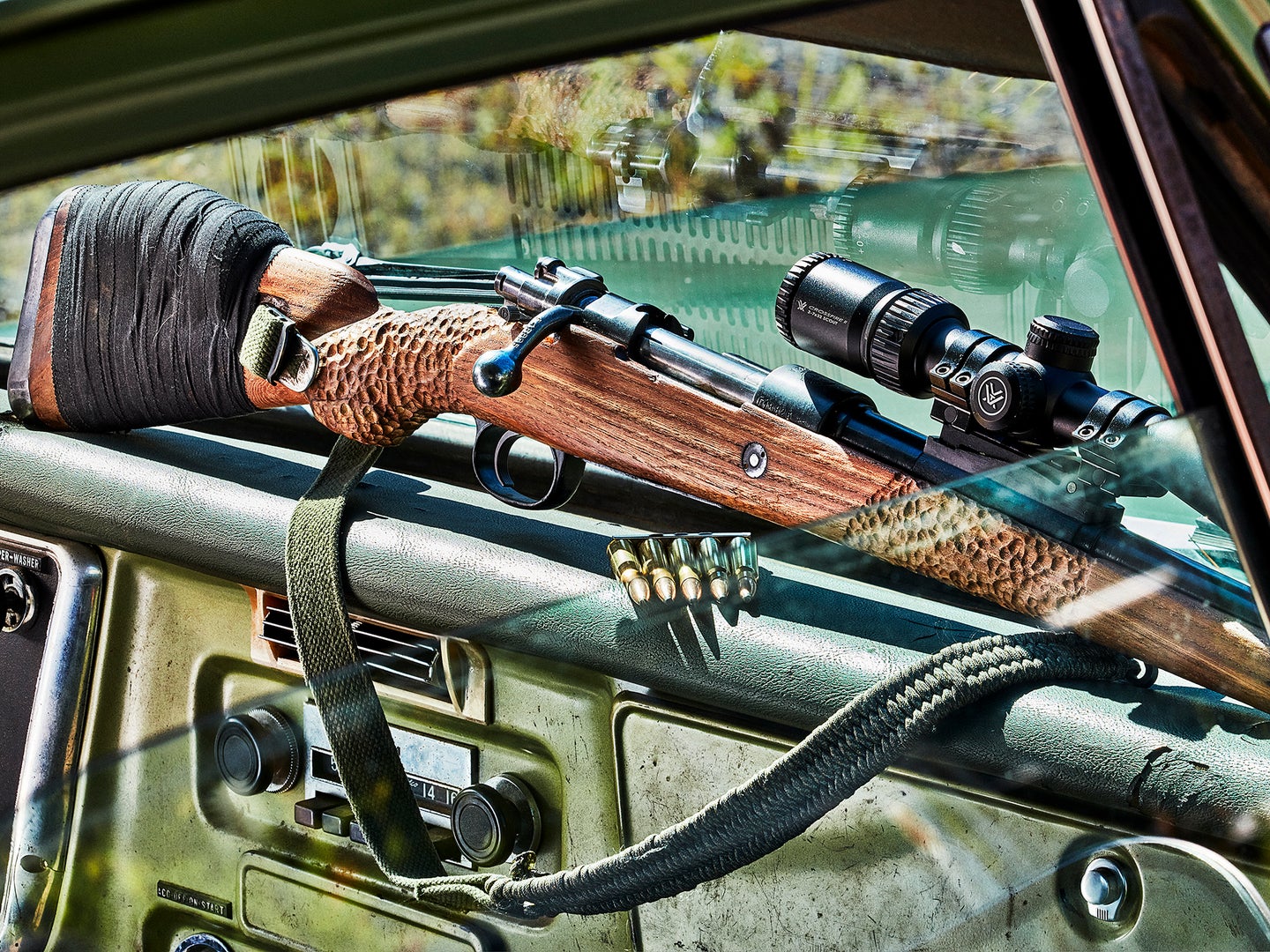 Scout rifle on the dash board of a pickup truck.