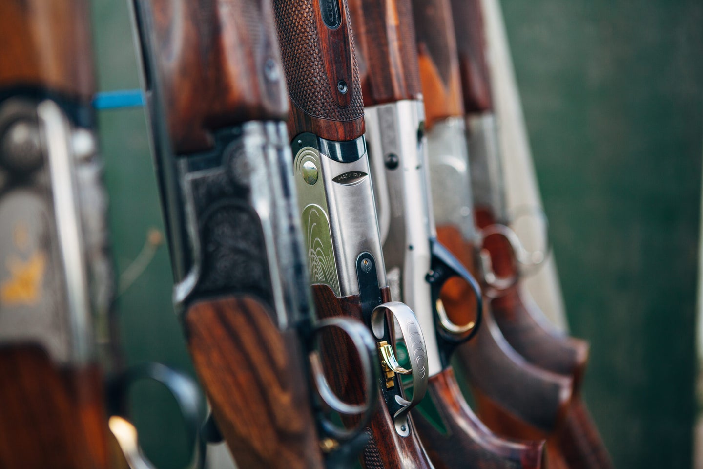 Various styles and types of sporting shotguns standing in a rack at a clay pigeon skeet shooting range.