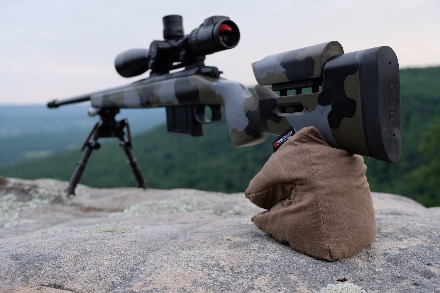 Rifle sitting on a rock with a pouch under the stock.