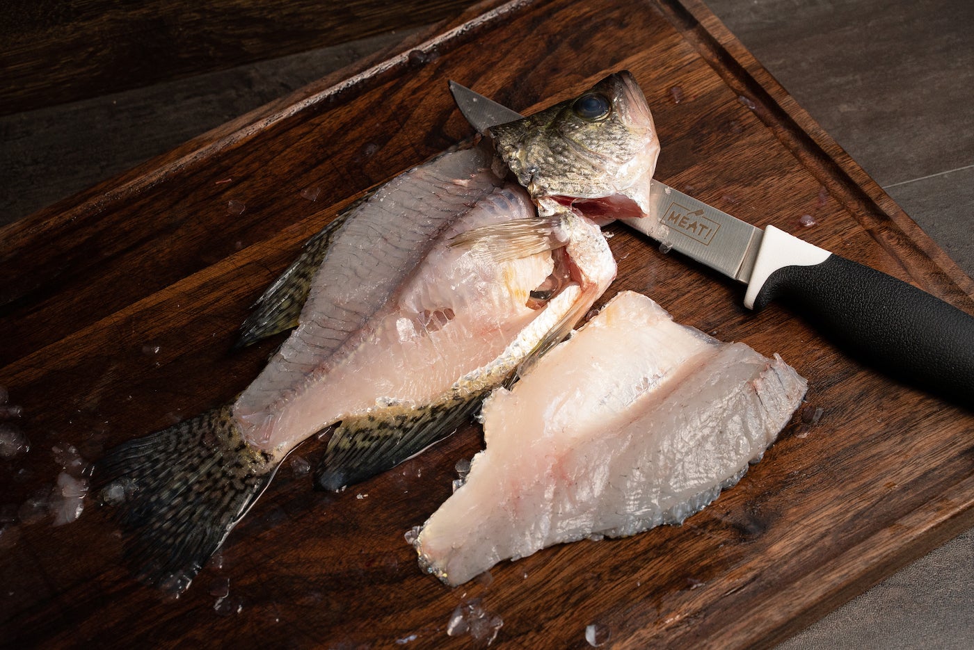 Filleted fish on a cutting board next to a knife. 
