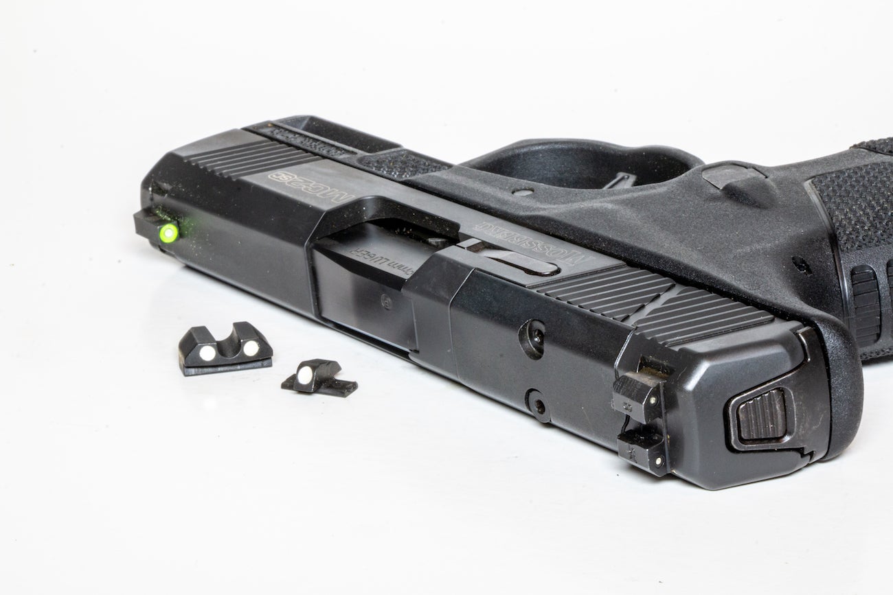 Handgun sitting on a white background with aftermarket sights.