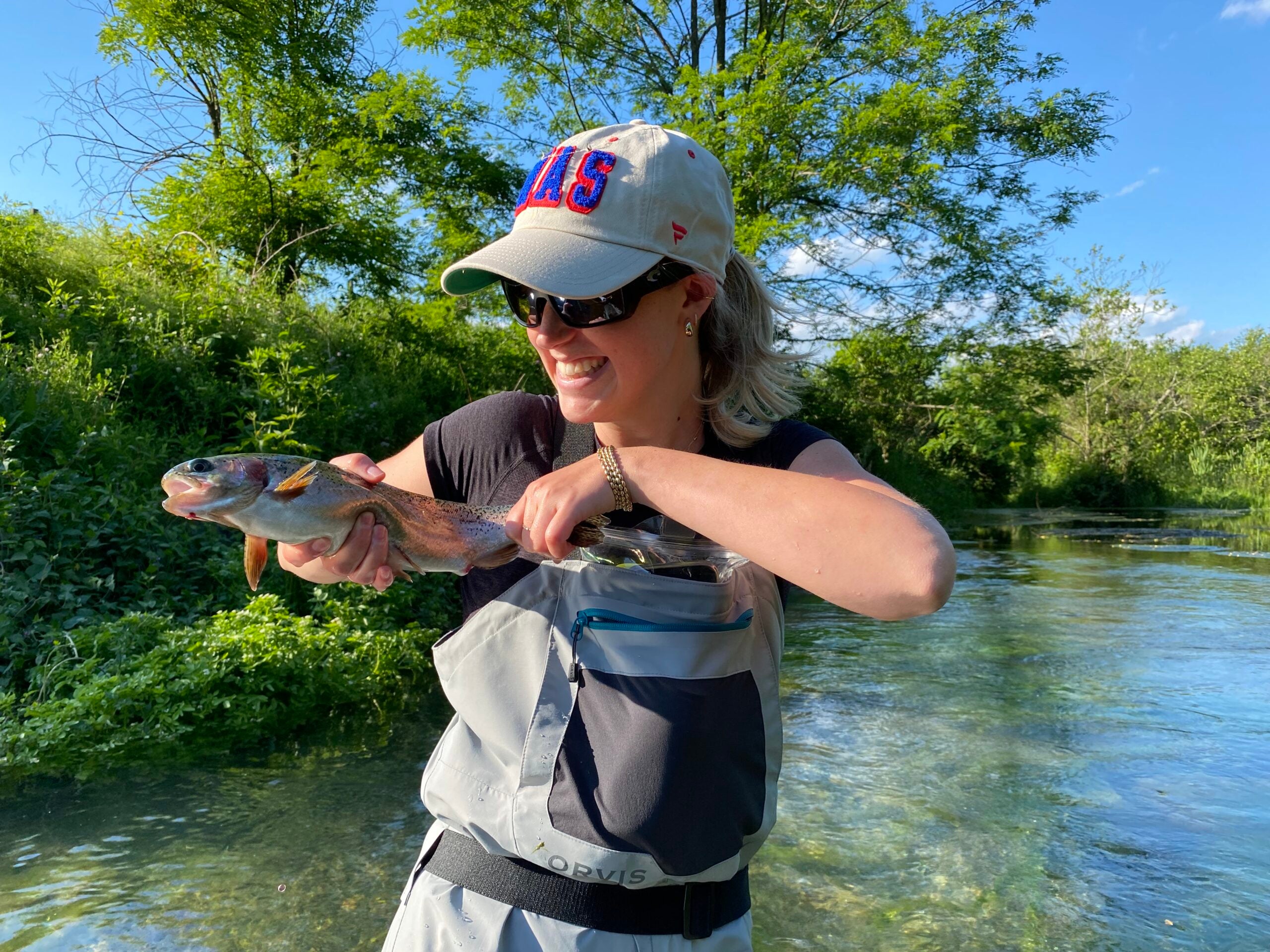 Woman holding rainbow trout in a river.