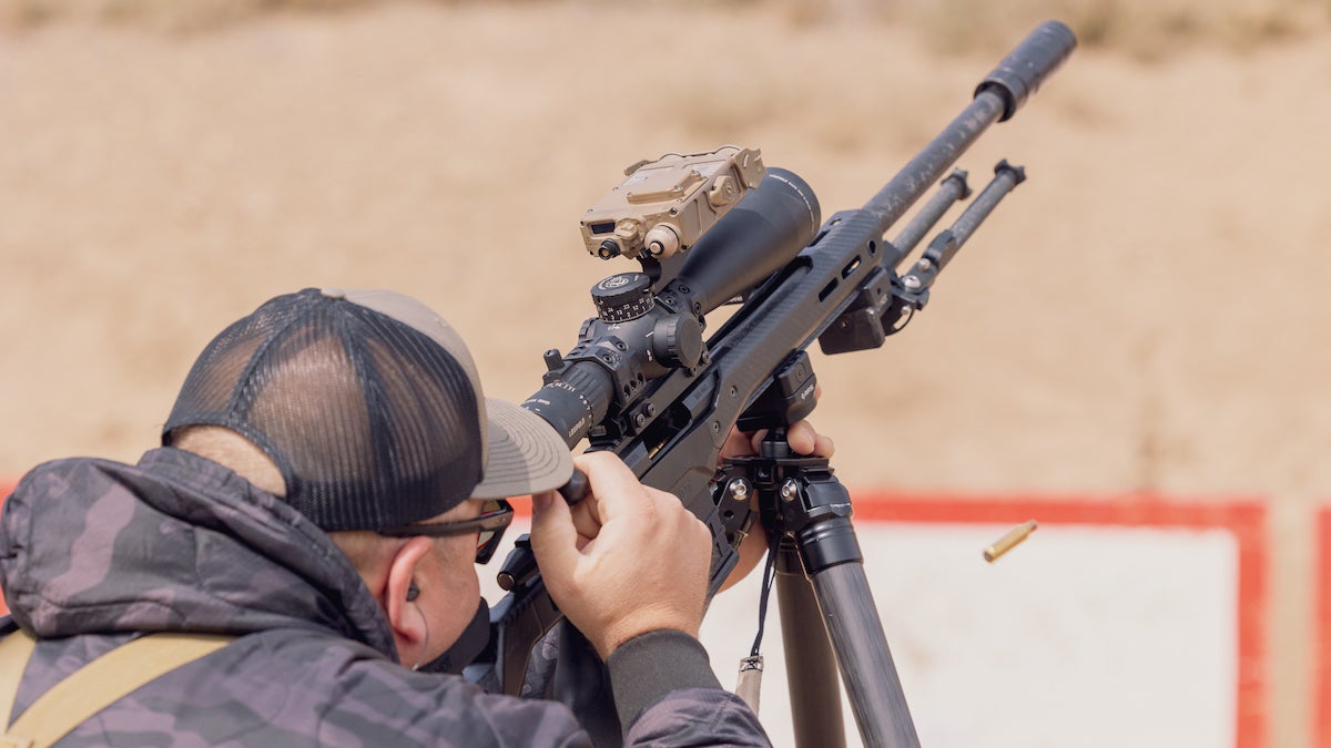 Man shooting a sniper rifle uphill.