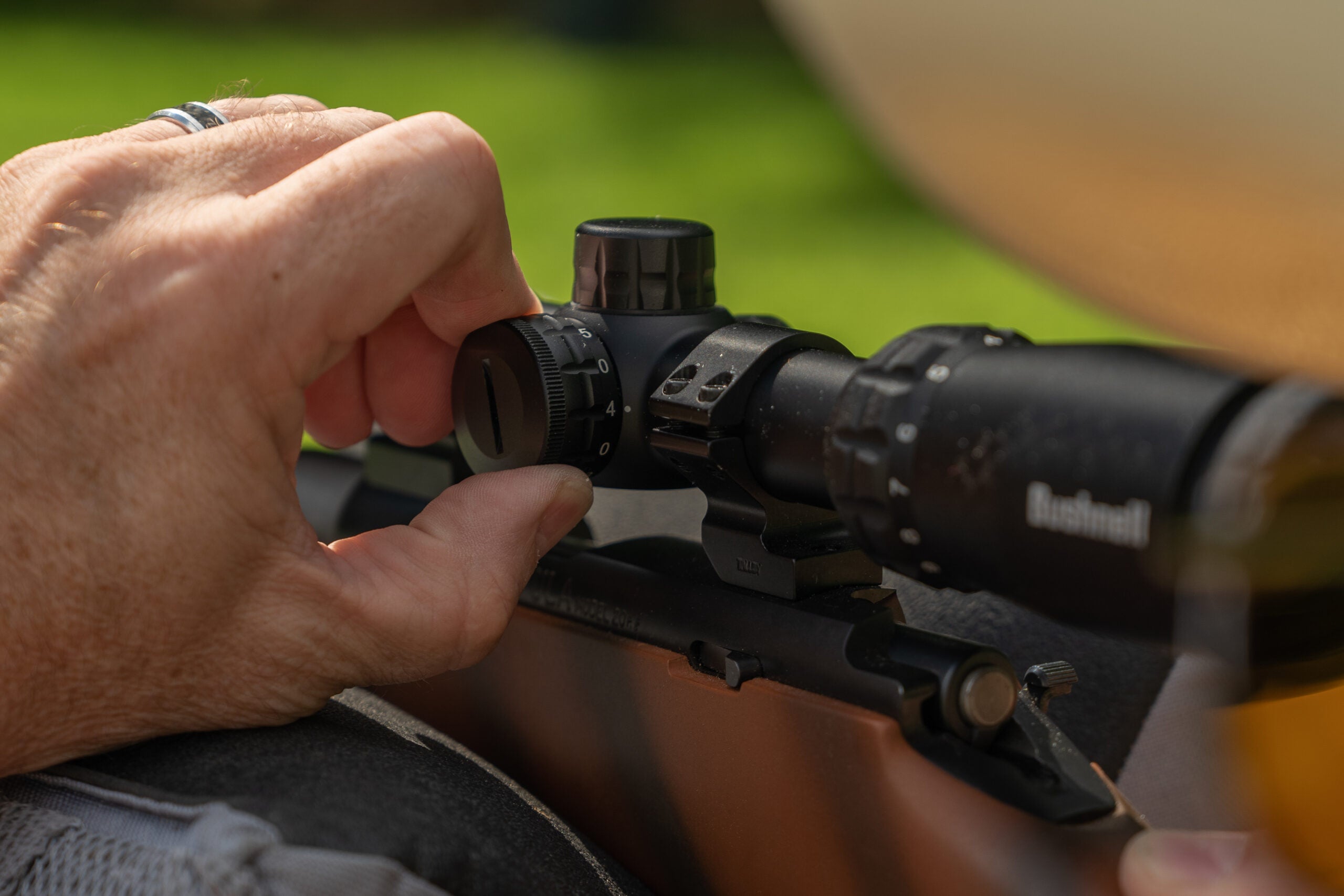 Hand adjusting brightness on a rifle scope.