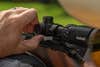 Hand adjusting brightness on a rifle scope.