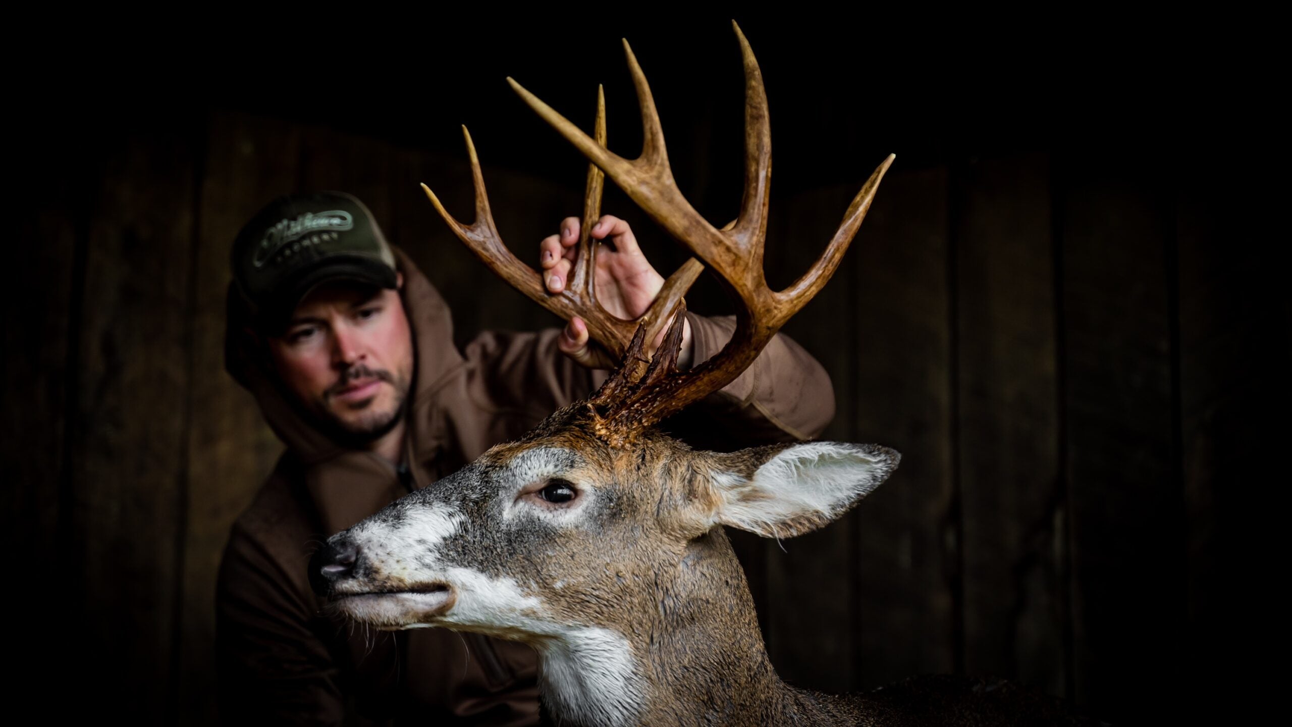man holds anglers of whitetail deer buck with patches of white on the deer's face