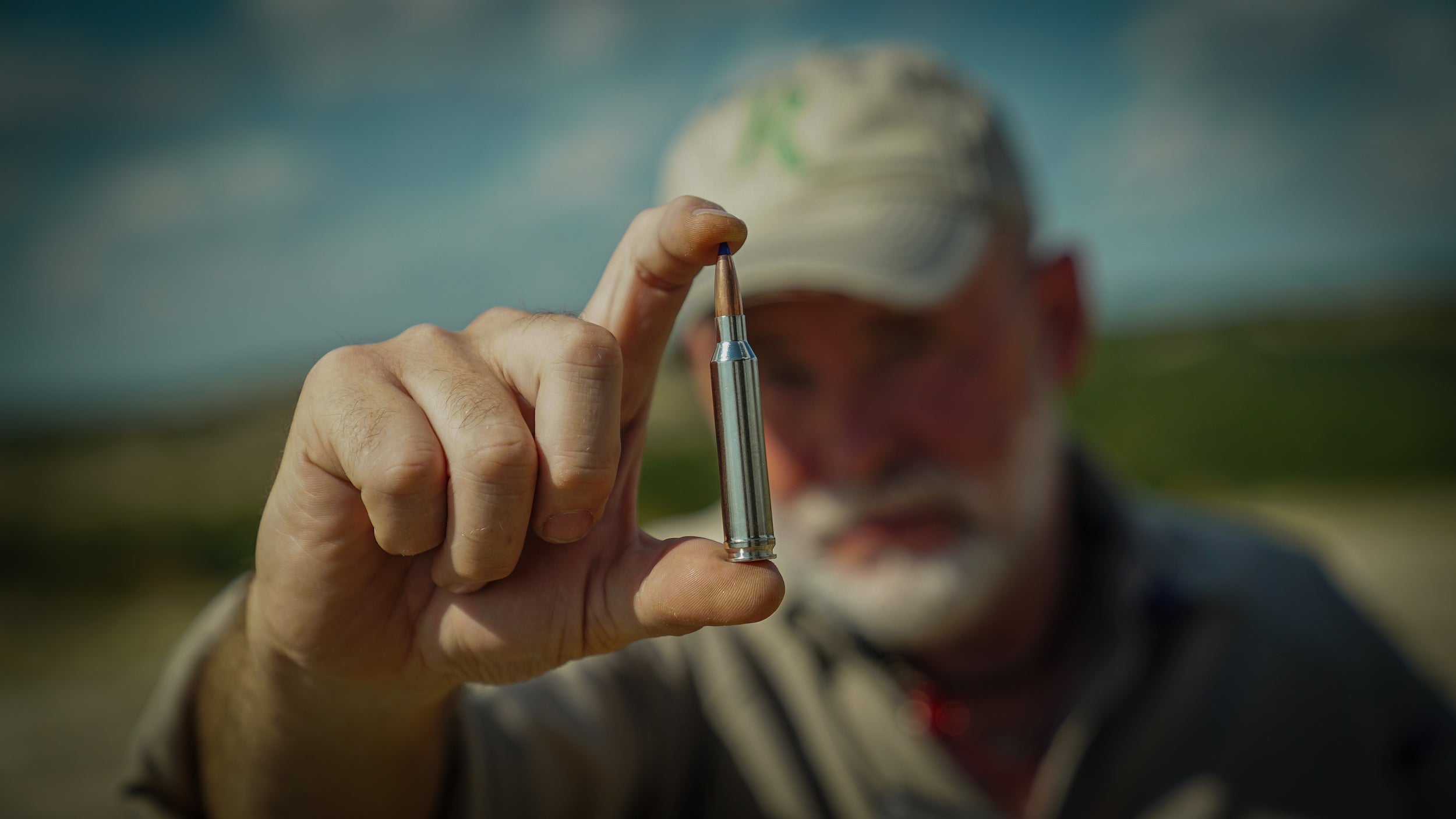 Man holding a hunting rifle cartridge.