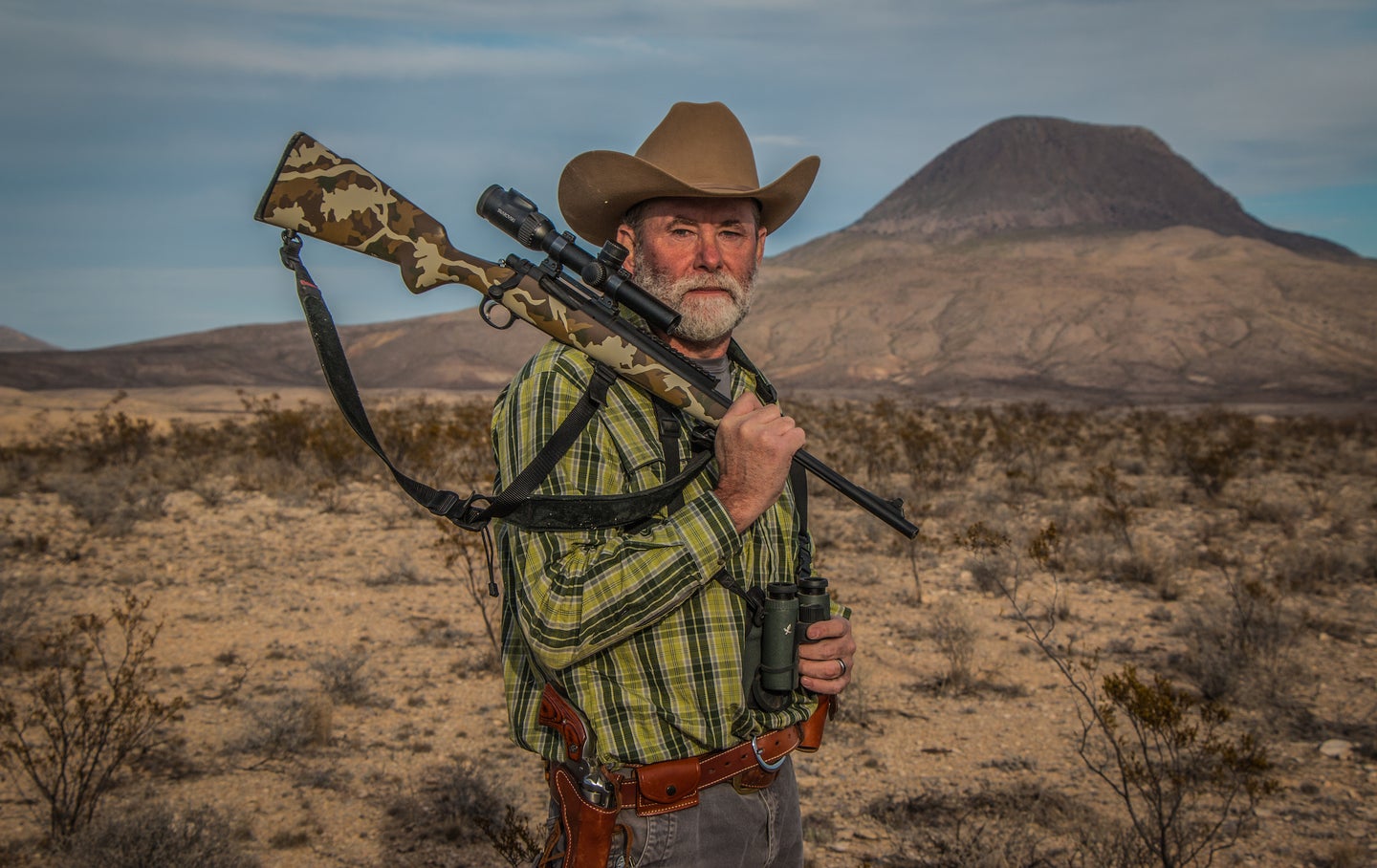 Man holding a great hunting rifle in a desert