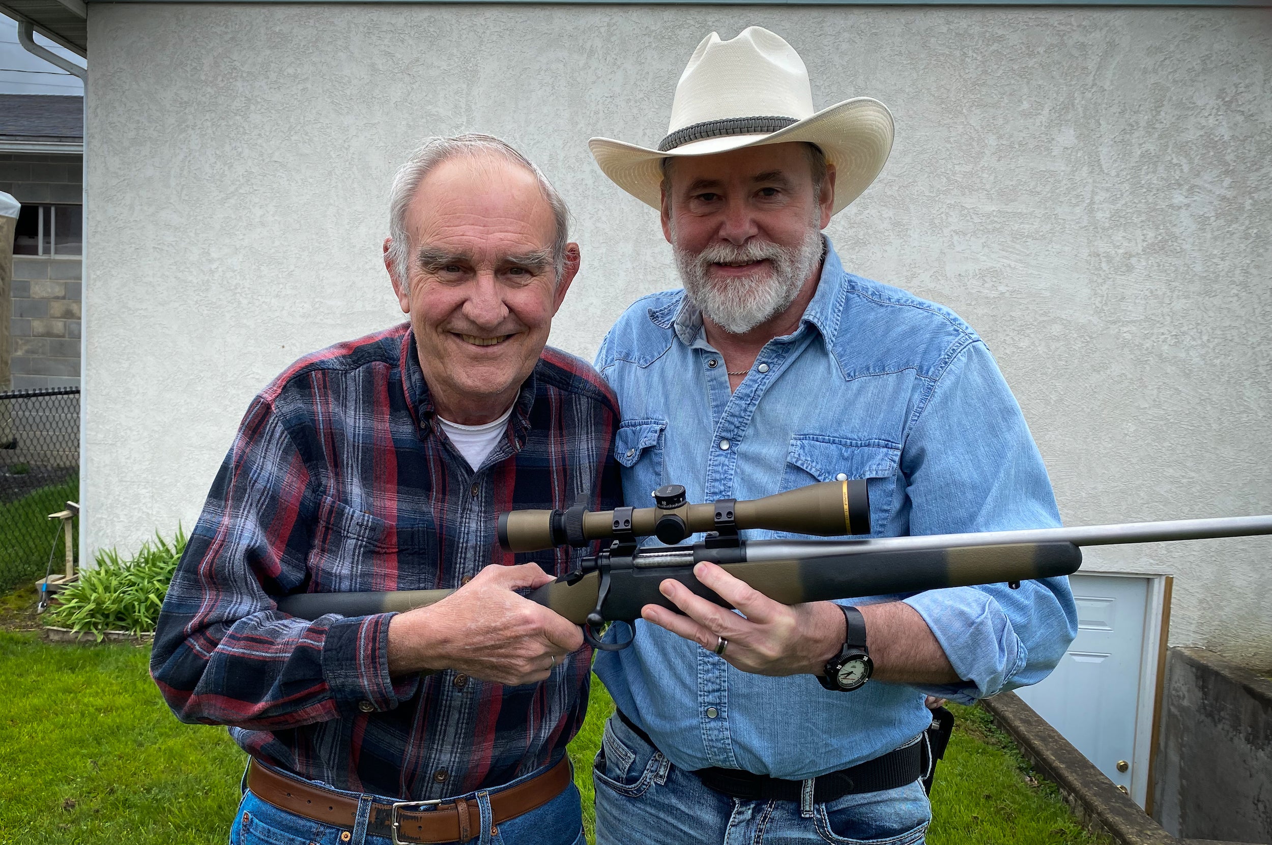Richard Mann and Melvin Forbes standing next to each other holding a rifle.