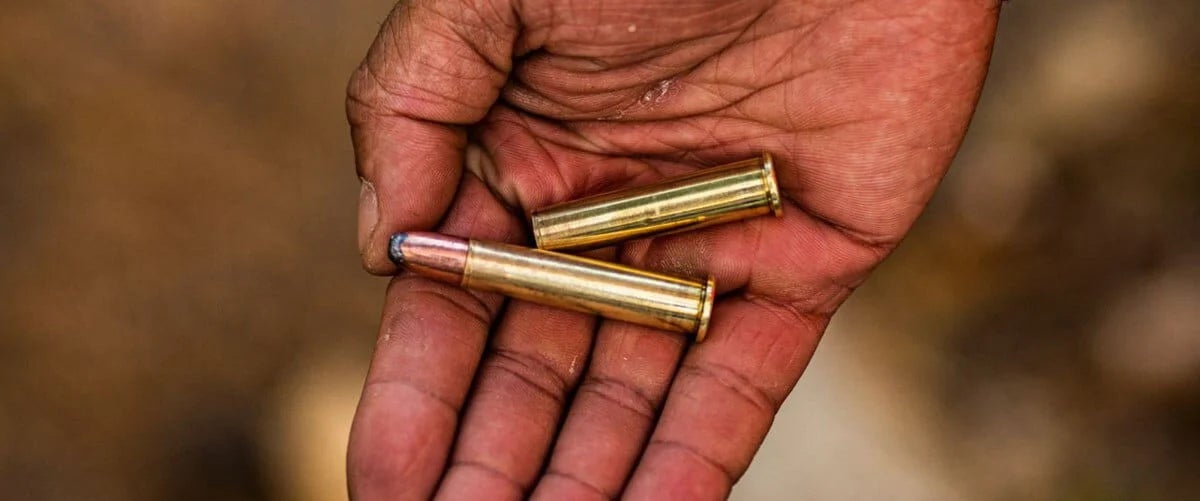hand with two rifle cartridges