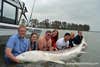 people pose in water with white sturgeon