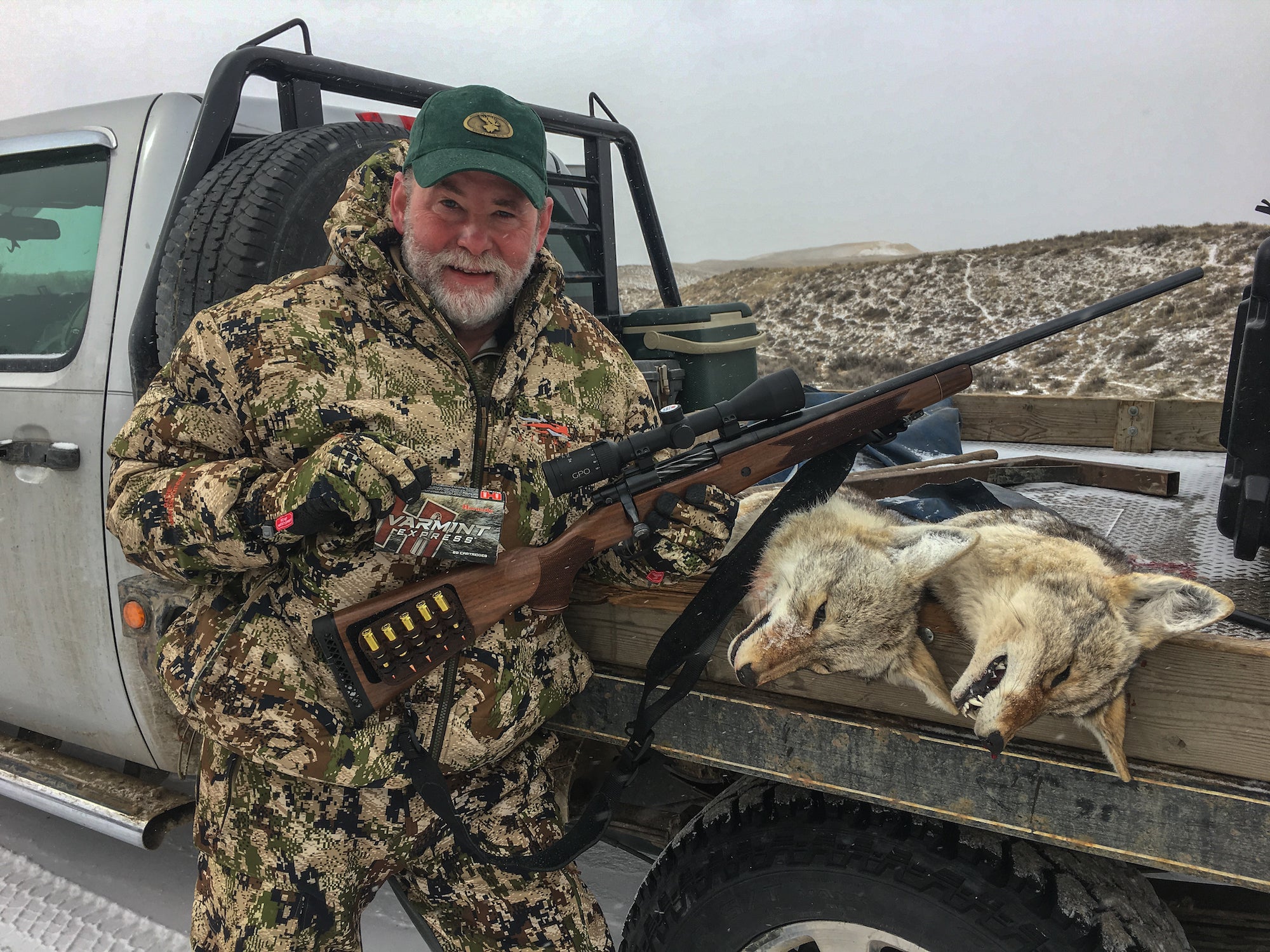 Hunter standing next to dead coyotes with a 6.5 creedmoor rifle.