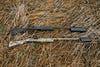 two shotguns with noise suppressors on straw