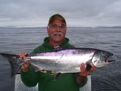 fisherman holds salmon on boat in ocean