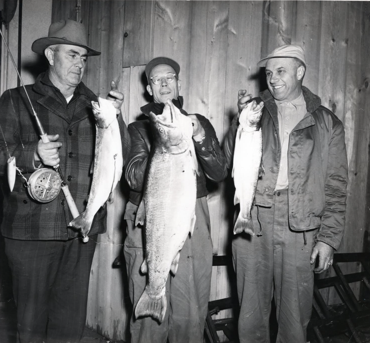 Trois hommes tenant du poisson.