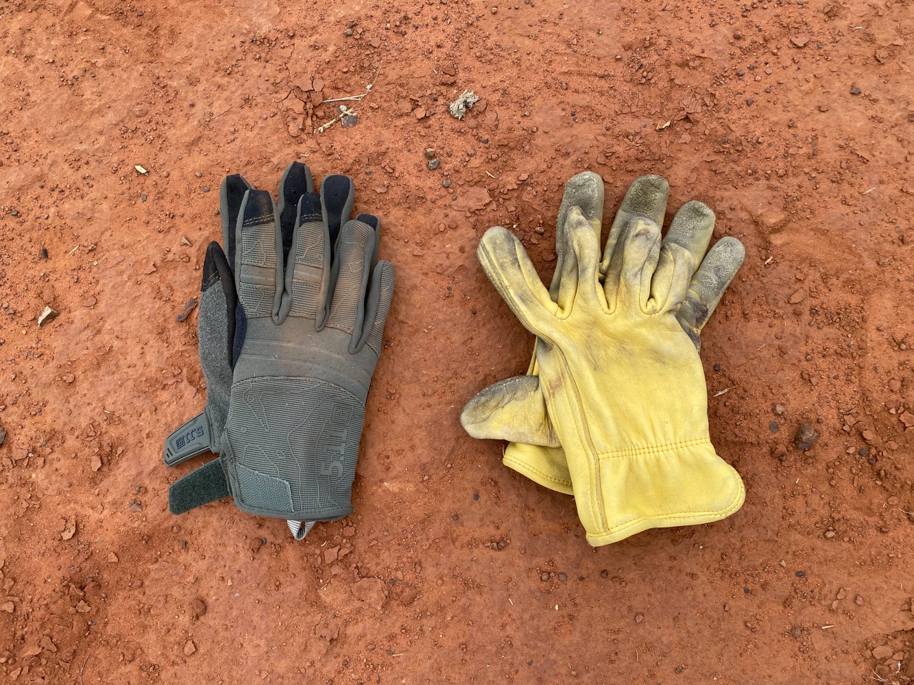 Two pairs of gloves in the dirt.