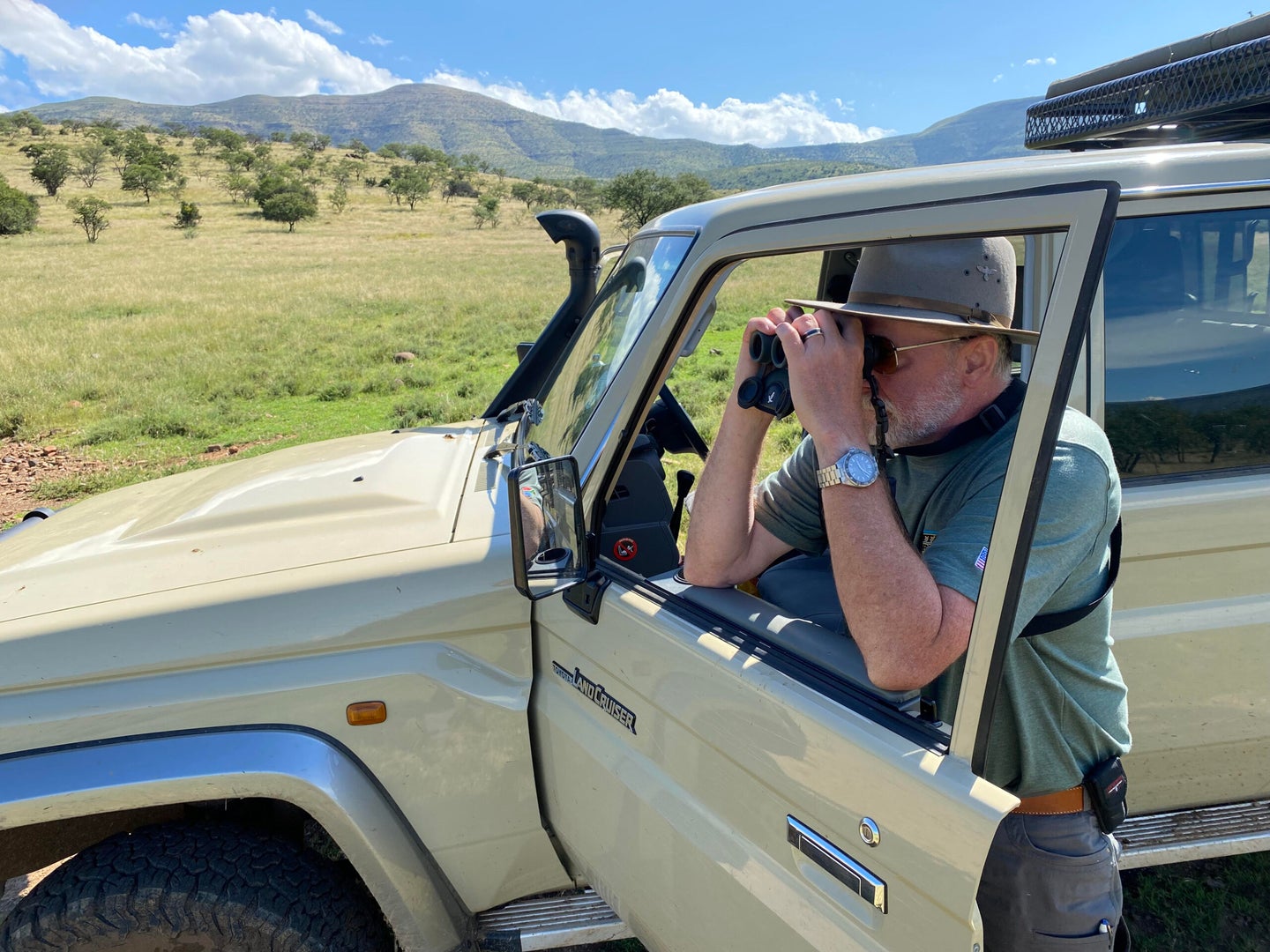 Man using binoculars on a truck door in Africa.