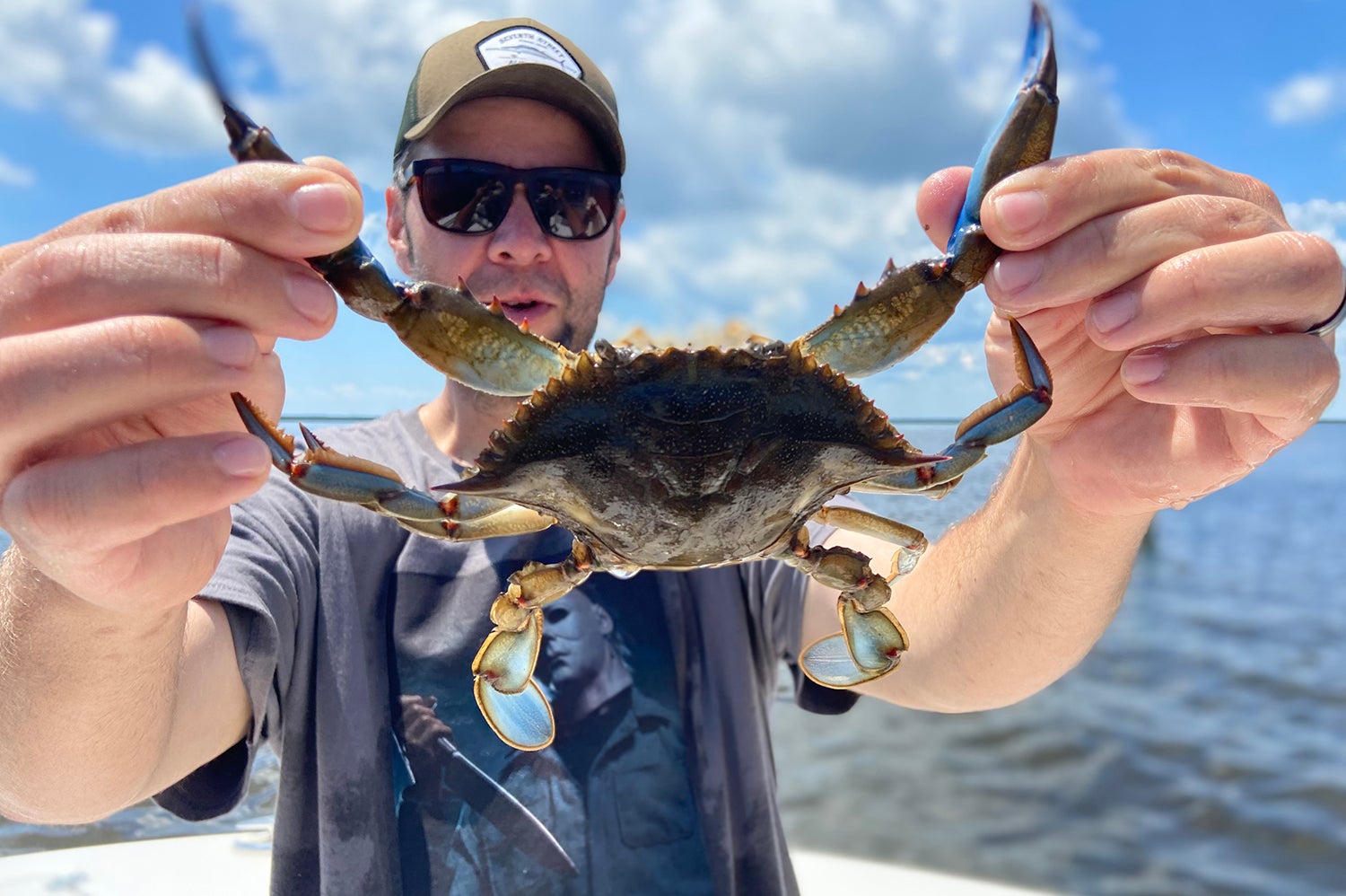 fisherman holds up a blue crab