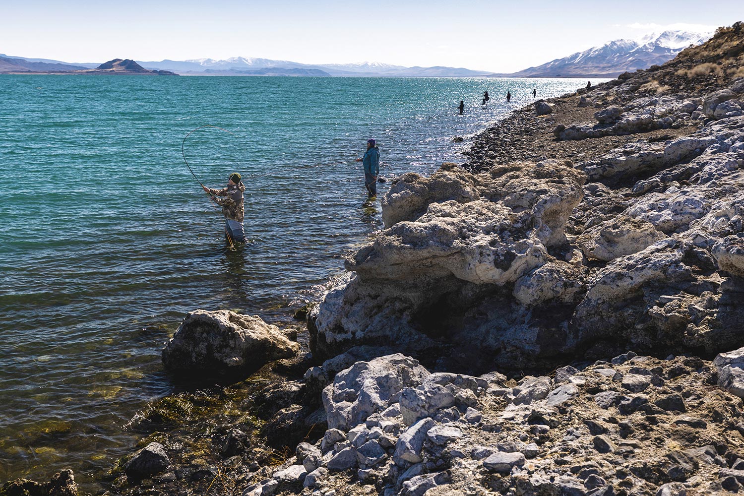 Anglers stand along shoreline to cast into big lake