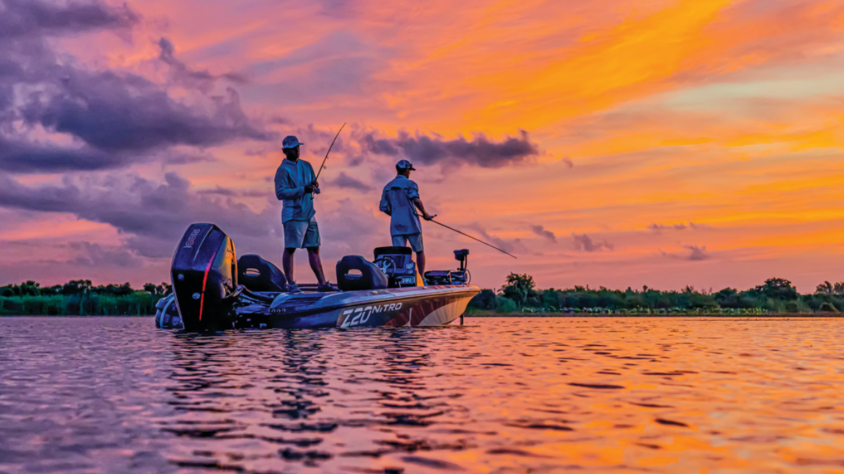Two anglers fishing on a tracker boat at sunset
