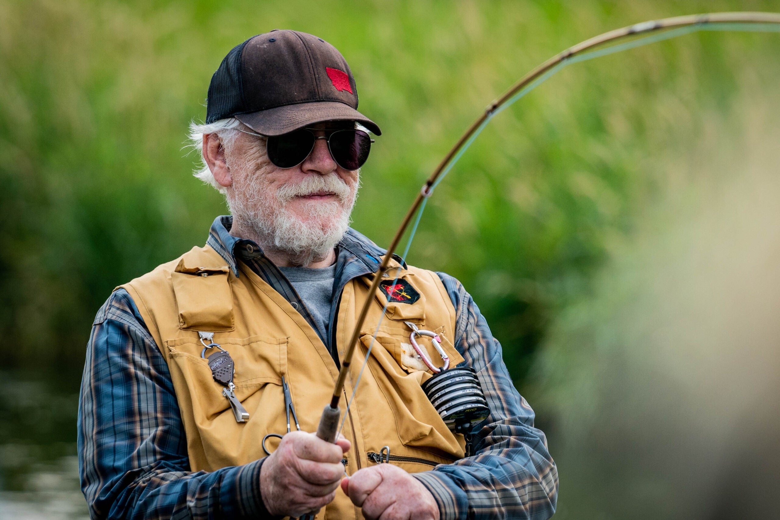 older man fights fish on fly rod