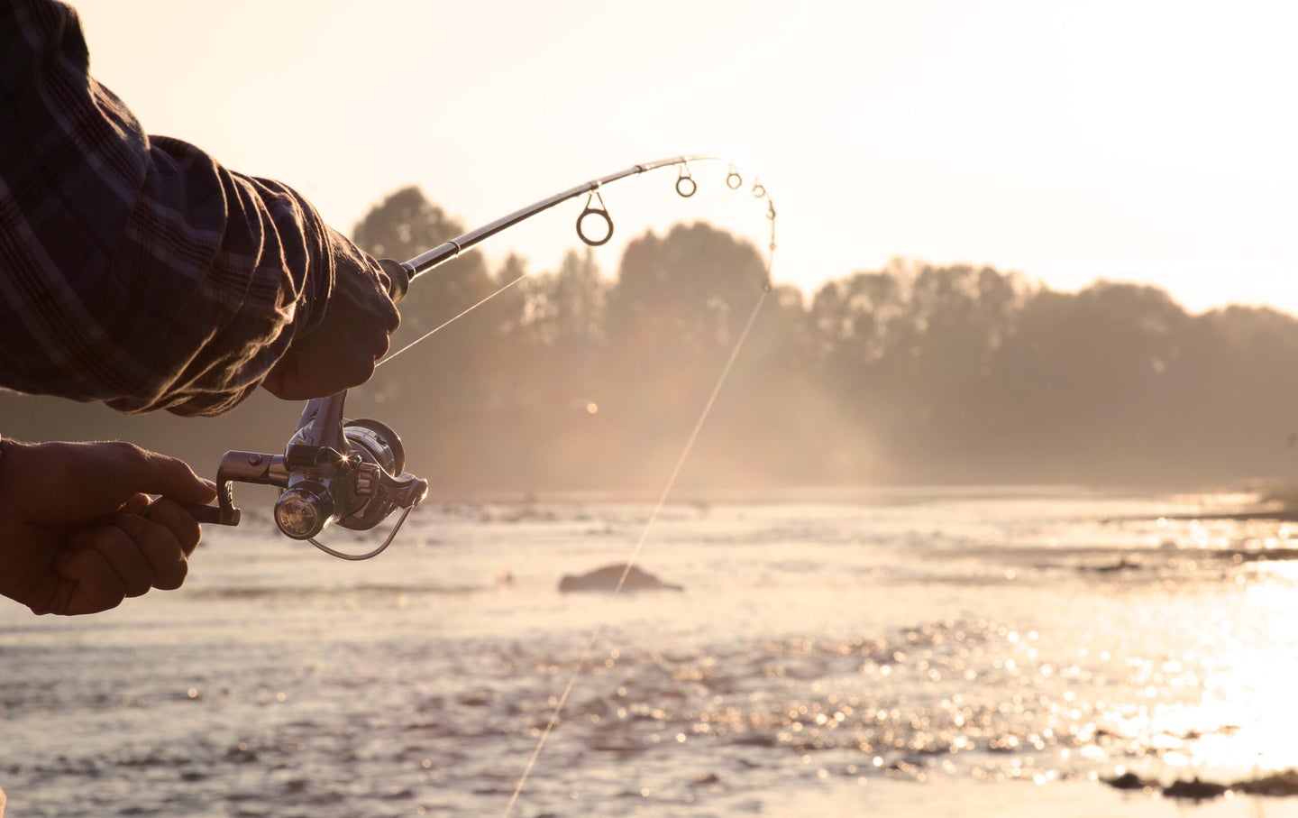 monofilament vs fluorocarbon: fisherman is fishing on a river in the early morning.