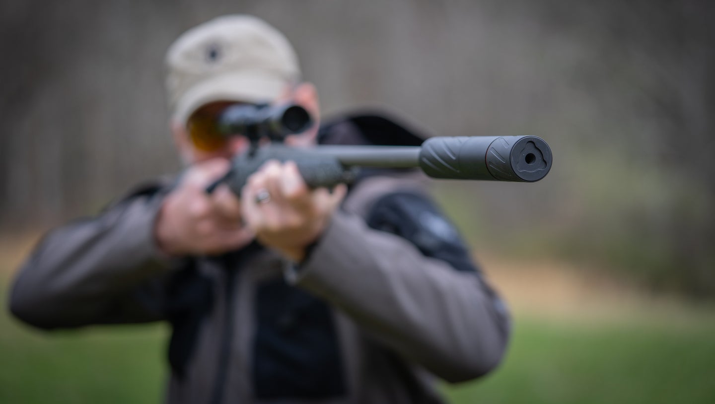 Man shooting a rifle with a suppressor.