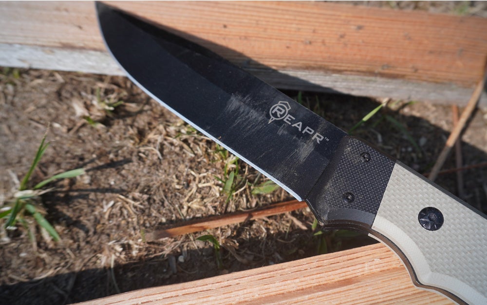 The black and tan Reapr Brigade knife on a split log. 