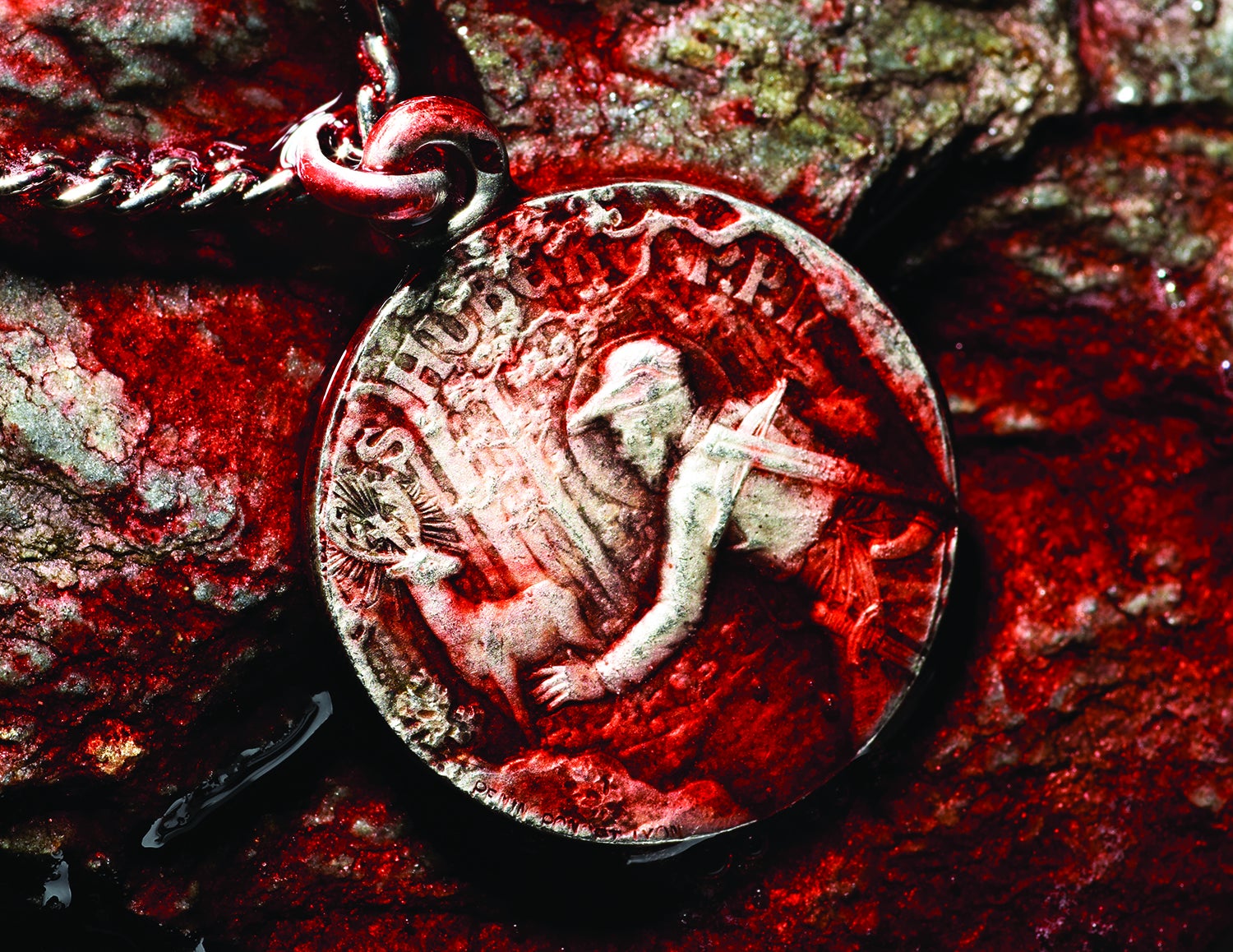 medallion of hunter with crossbow and deer is covered with blood on rocky background