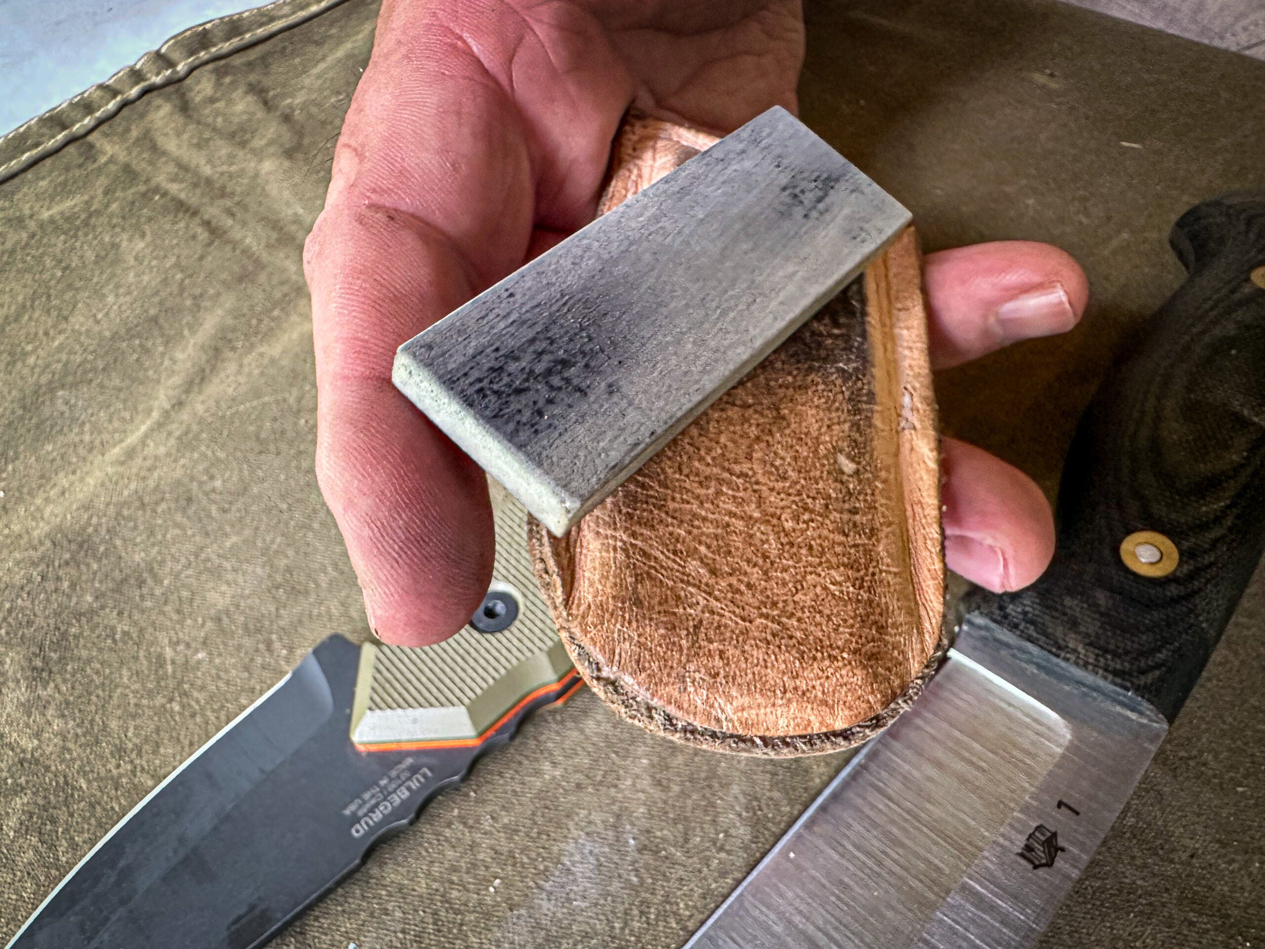 Small knife sharpening stone sits on a leather case