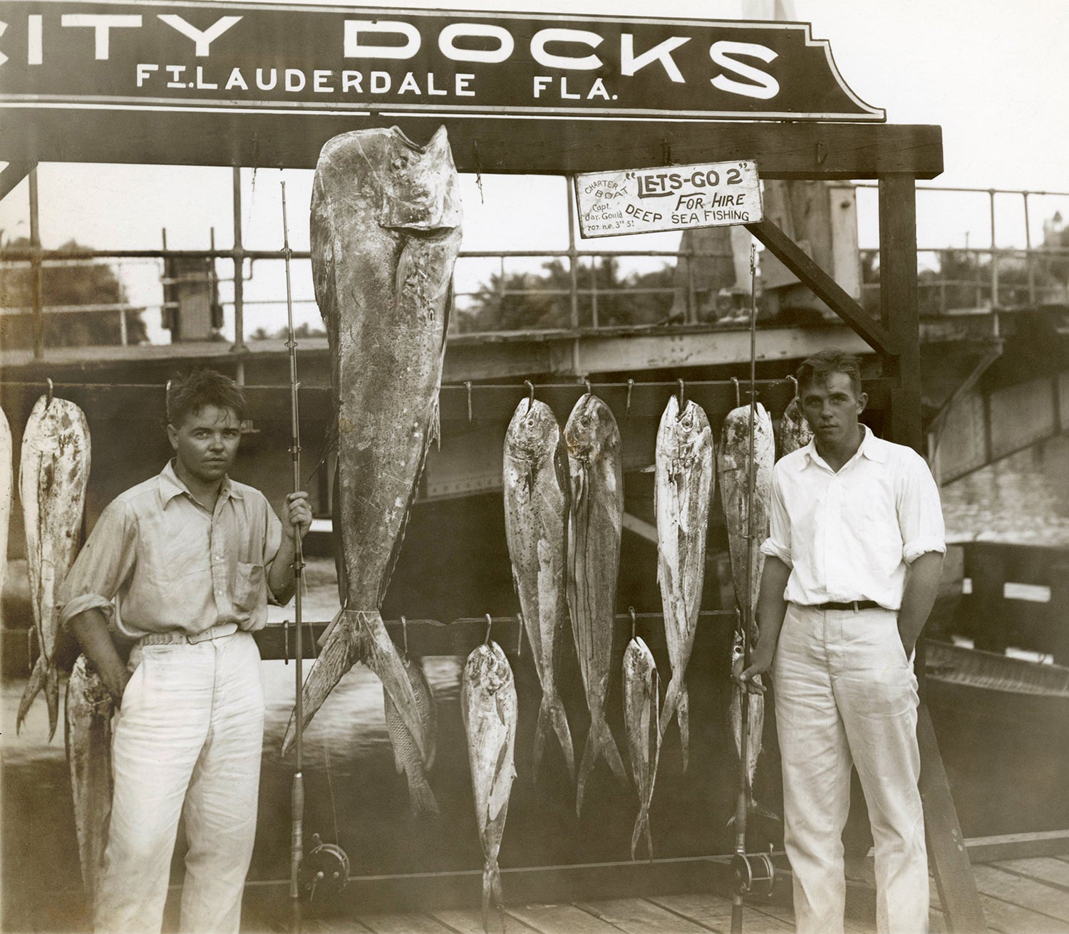 two anglers pose with a many mahi on a dock in fort lauderdale