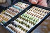 Open fly box shows many flies organized by size and type.