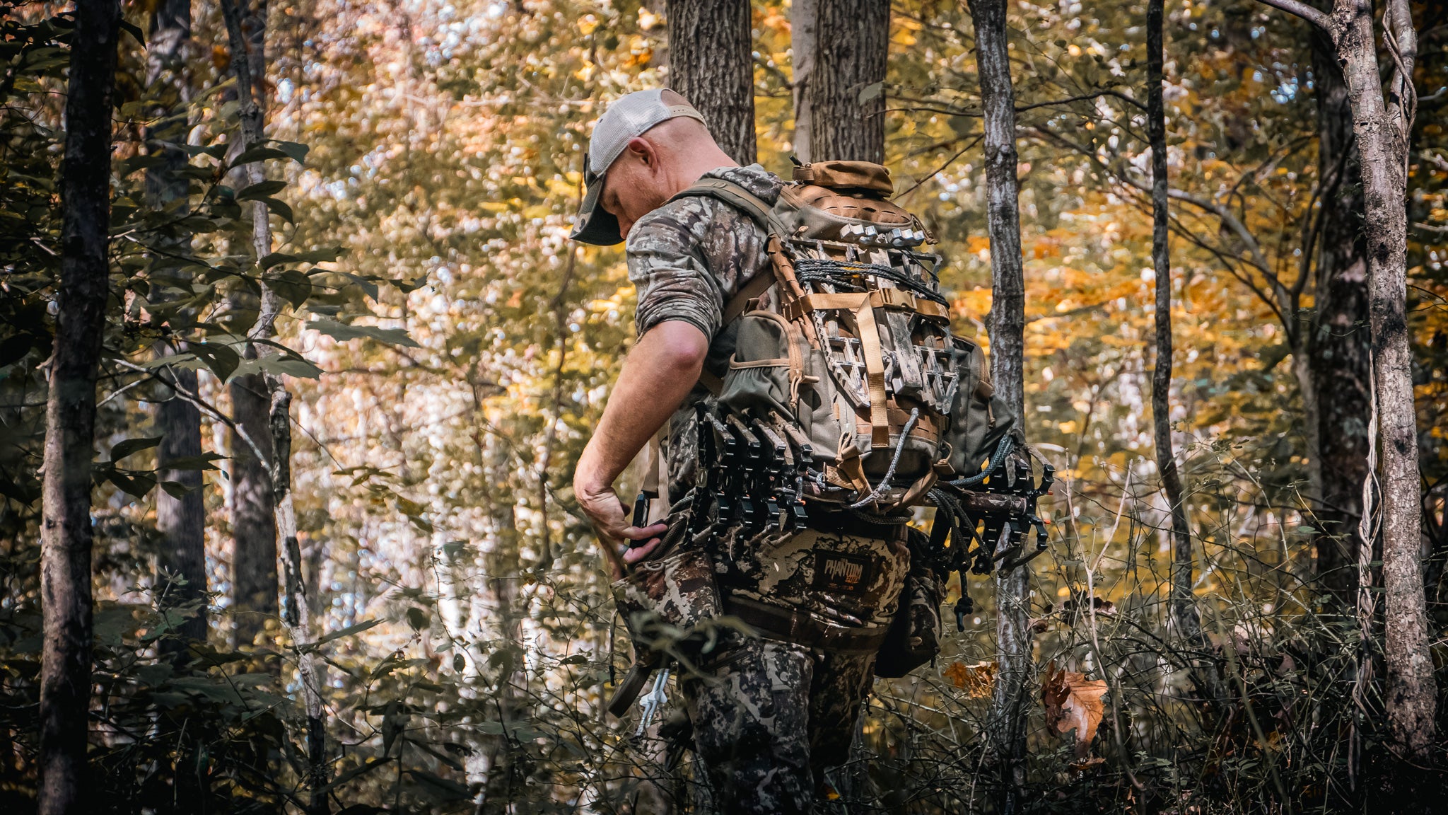 photo of hunter walking into the woods with a tree saddle on his back