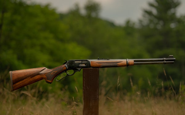 marlin rifle balanced on post with trees in background
