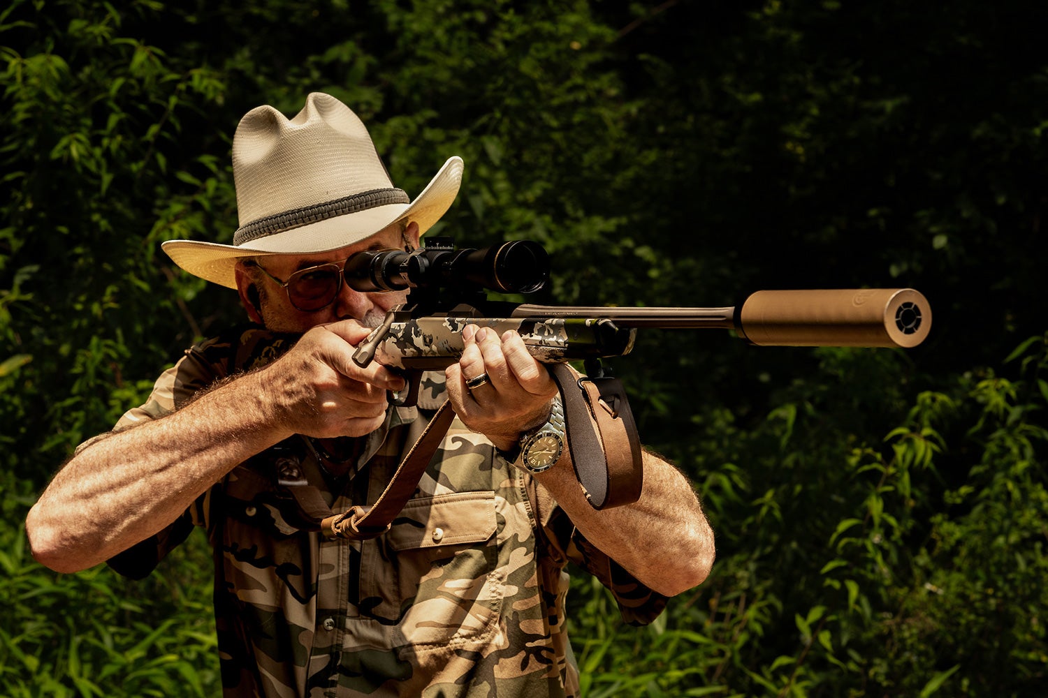 shooter aims rifle with large suppressor