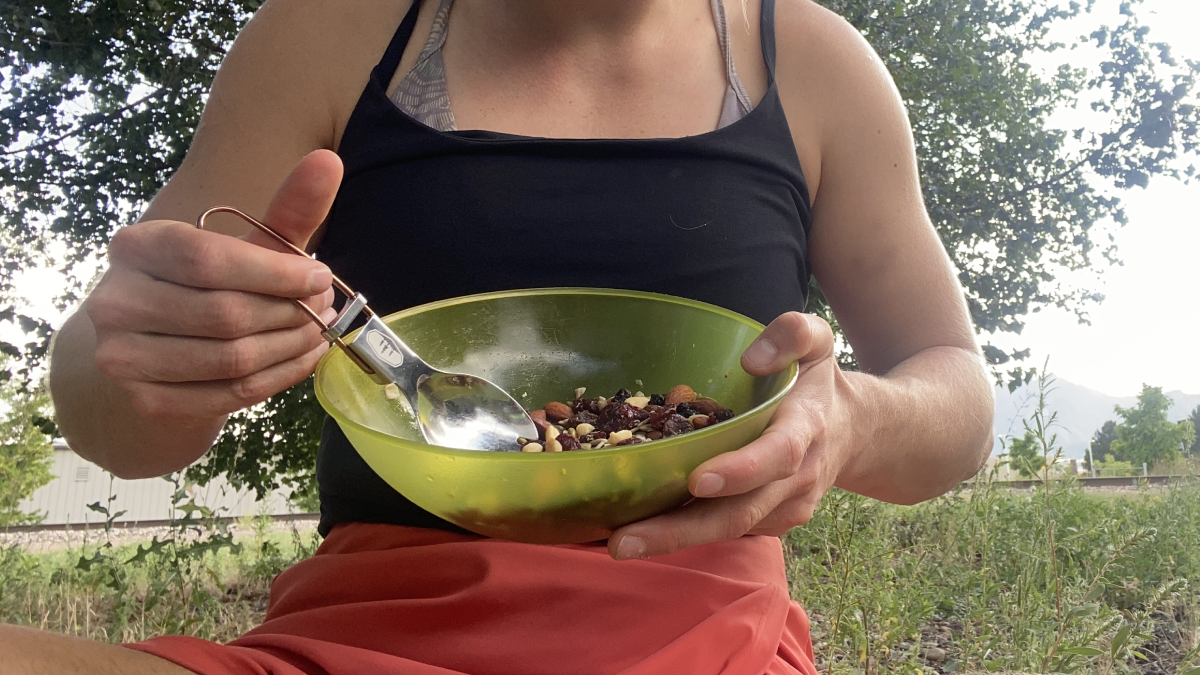 Woman using GSI Glacier Folding Spork to eat a camping meal