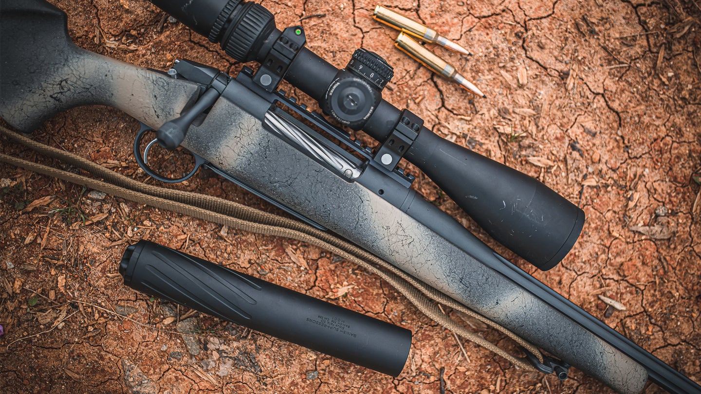 photo of a hunting rifle with ammunition and a suppressor
