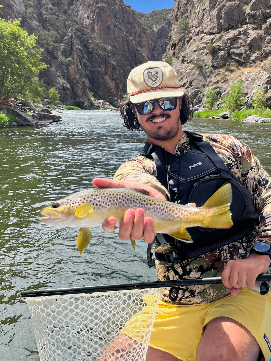 fly fisherman holds a brown trout