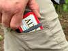 Outdoorsman slides an altoids tin survival kit into his pocket.