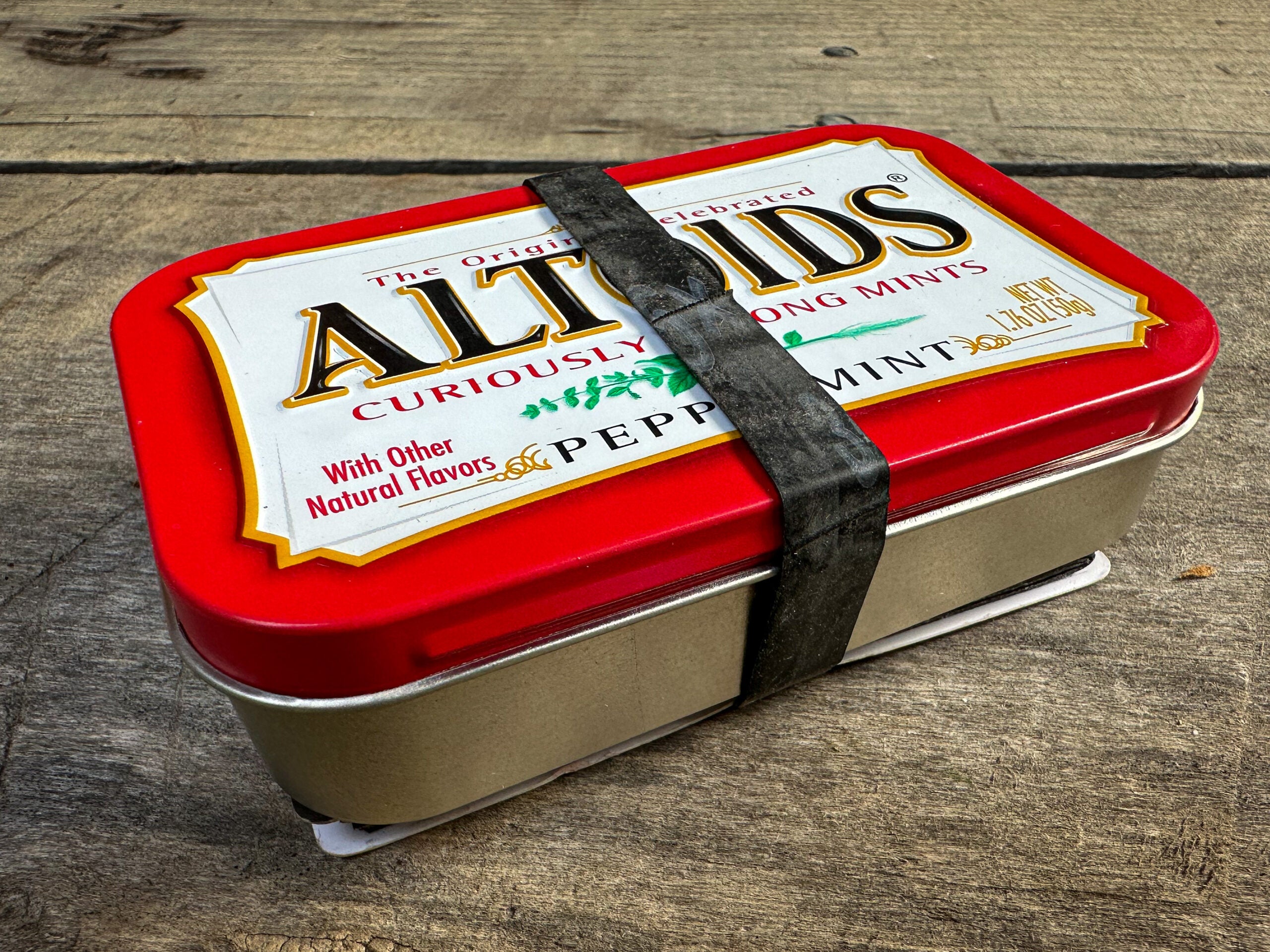 Rubber band is secured around an Altoids tin.