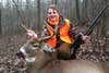 young boy in camo and orange grins and poses with whitetail buck