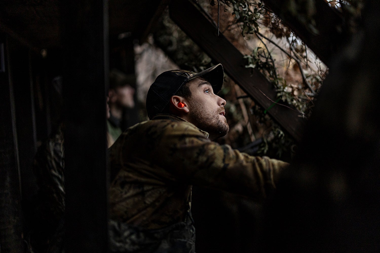hunter peers out of duck blind during low light