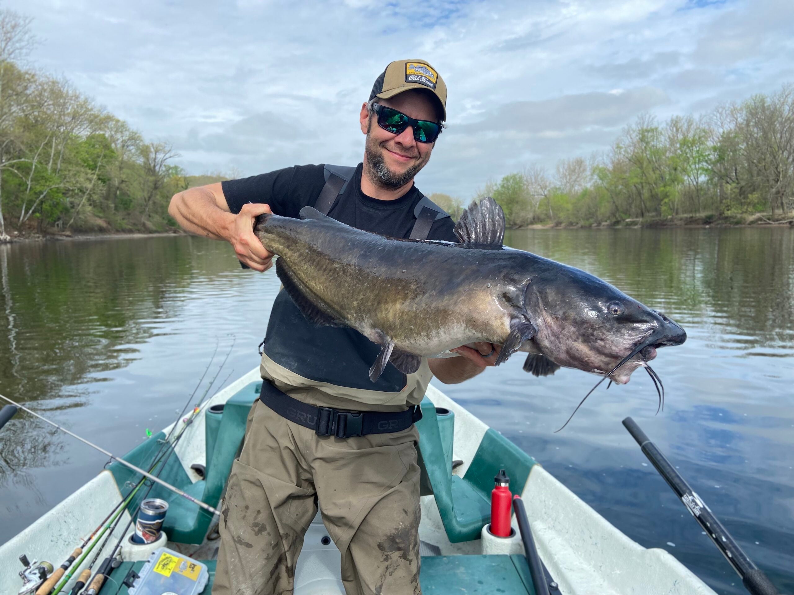 Fisherman holds a channel catfish in a boat